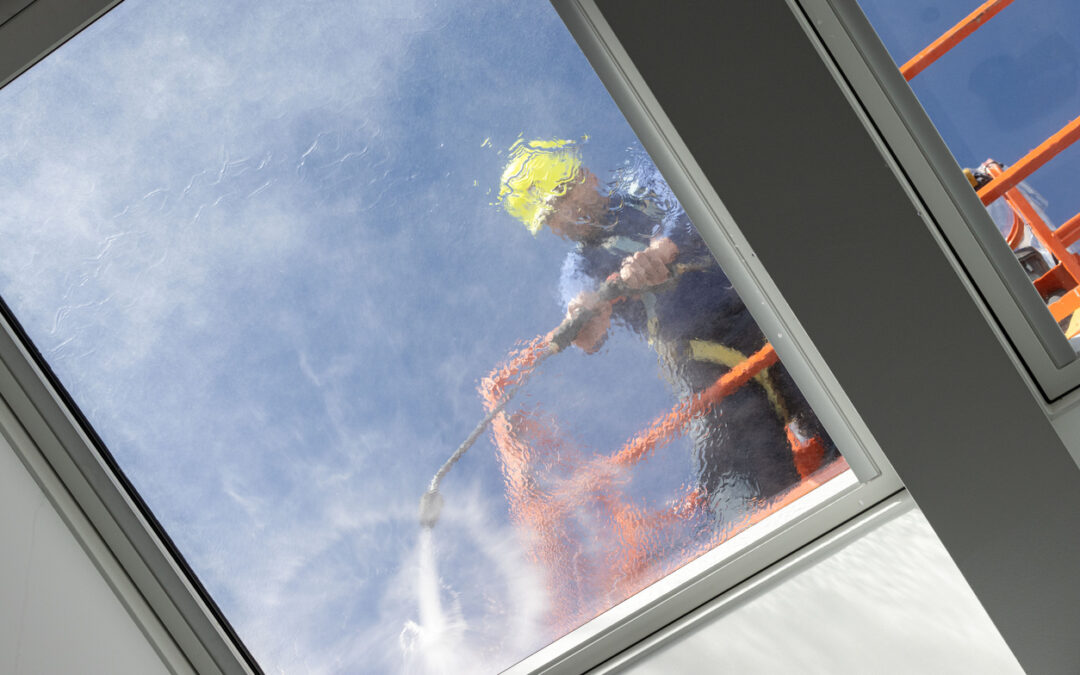 Technician cleaning an exterior skylight surface to improve clarity and maintain optimal skylight performance.